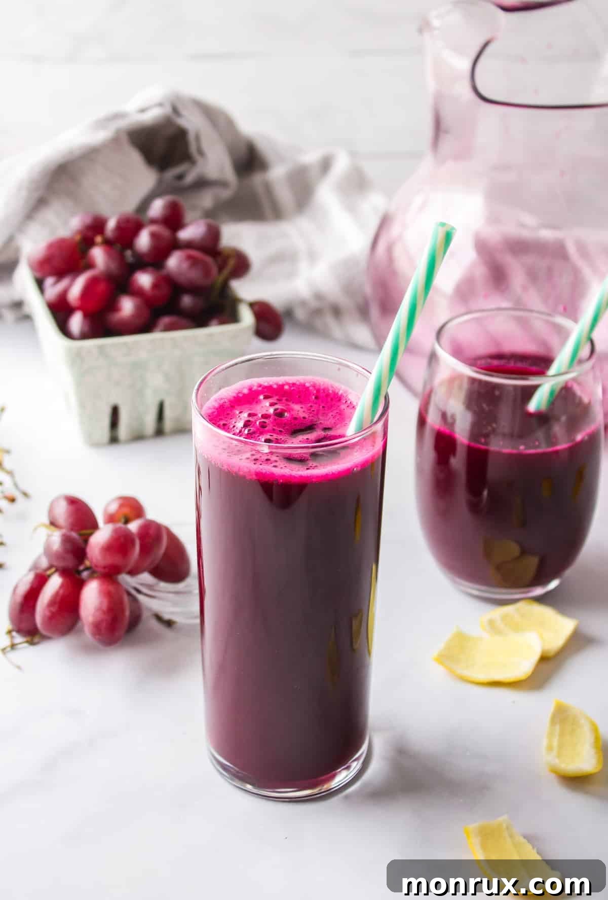 A vibrant glass of homemade purple juice with a straw, garnished with fresh purple grapes, ready to be enjoyed as a refreshing and healthy beverage.