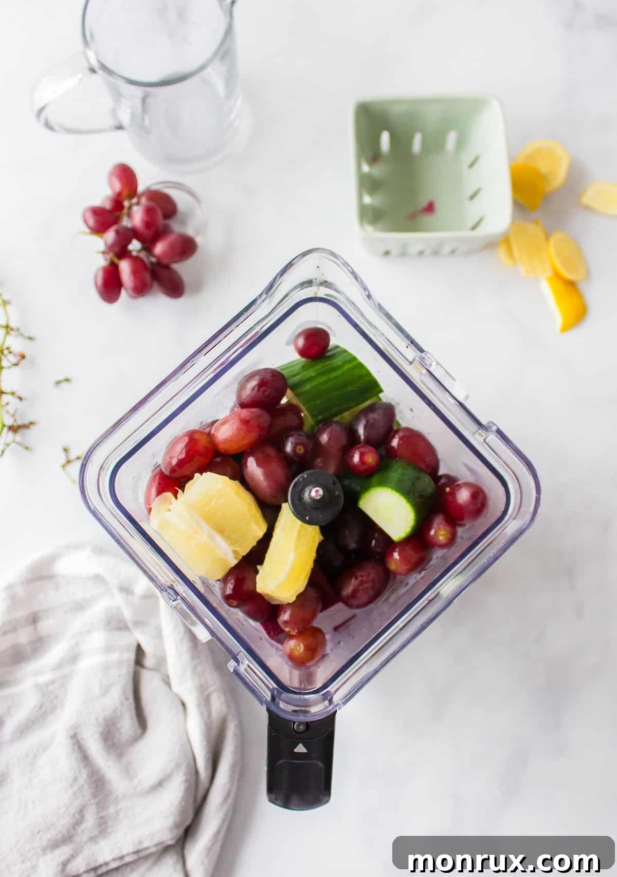 Step one of preparing purple juice: Fresh beets, purple grapes, cucumber, and lemon are cleaned and cut into pieces on a cutting board, ready for juicing or blending.