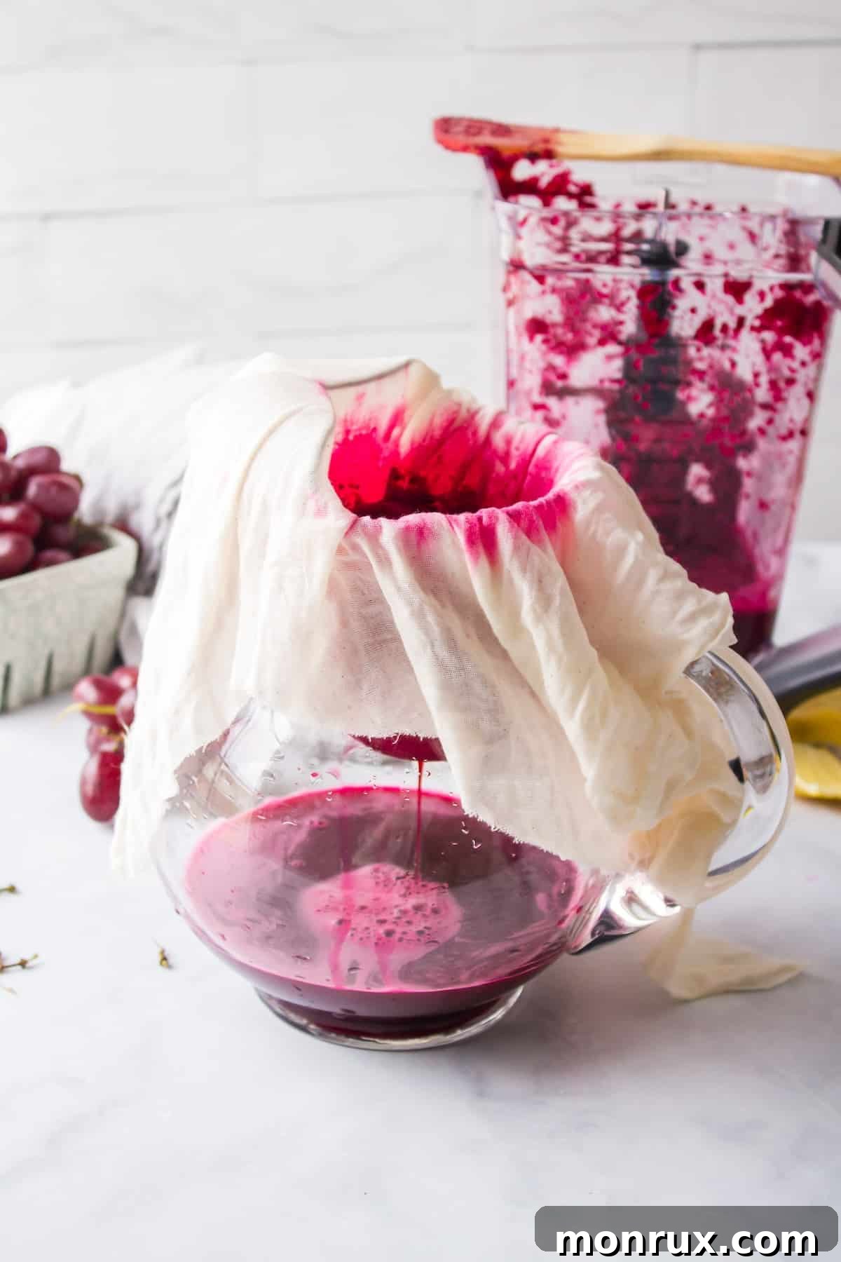 Step three of making purple juice: Pouring the blended or juiced mixture through a nut milk bag or fine-mesh strainer to separate the liquid from the pulp, ensuring a smooth texture.