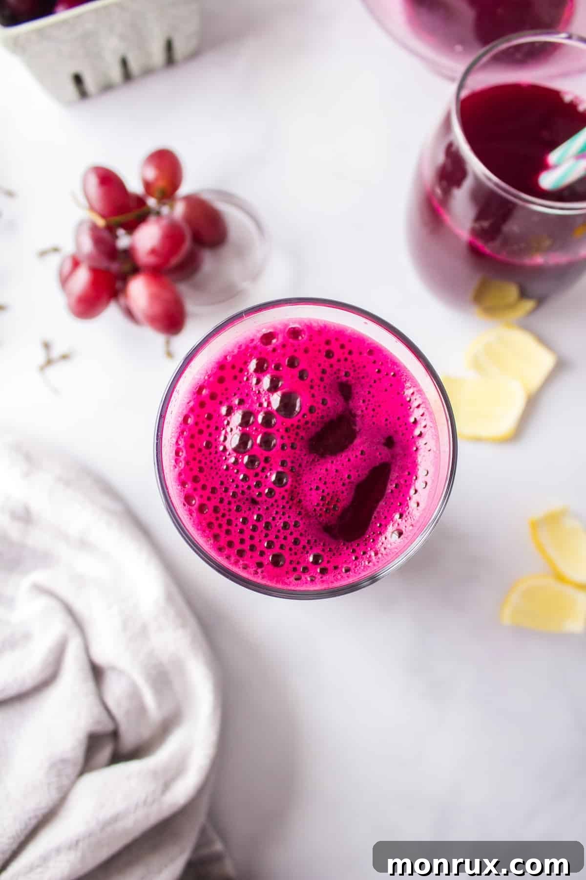 Step four of making purple juice: A freshly poured glass of vibrant purple juice, garnished with fresh grapes and a lemon slice, ready to be served immediately.