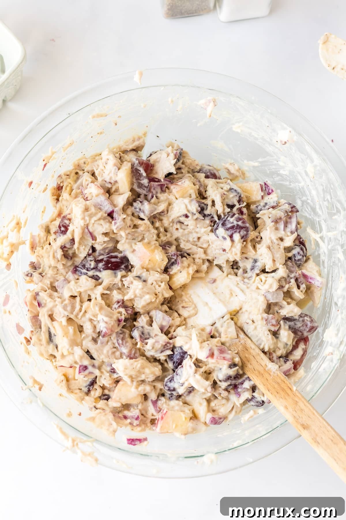 Apple Pecan Chicken Salad ingredients being mixed in a bowl with a spatula.