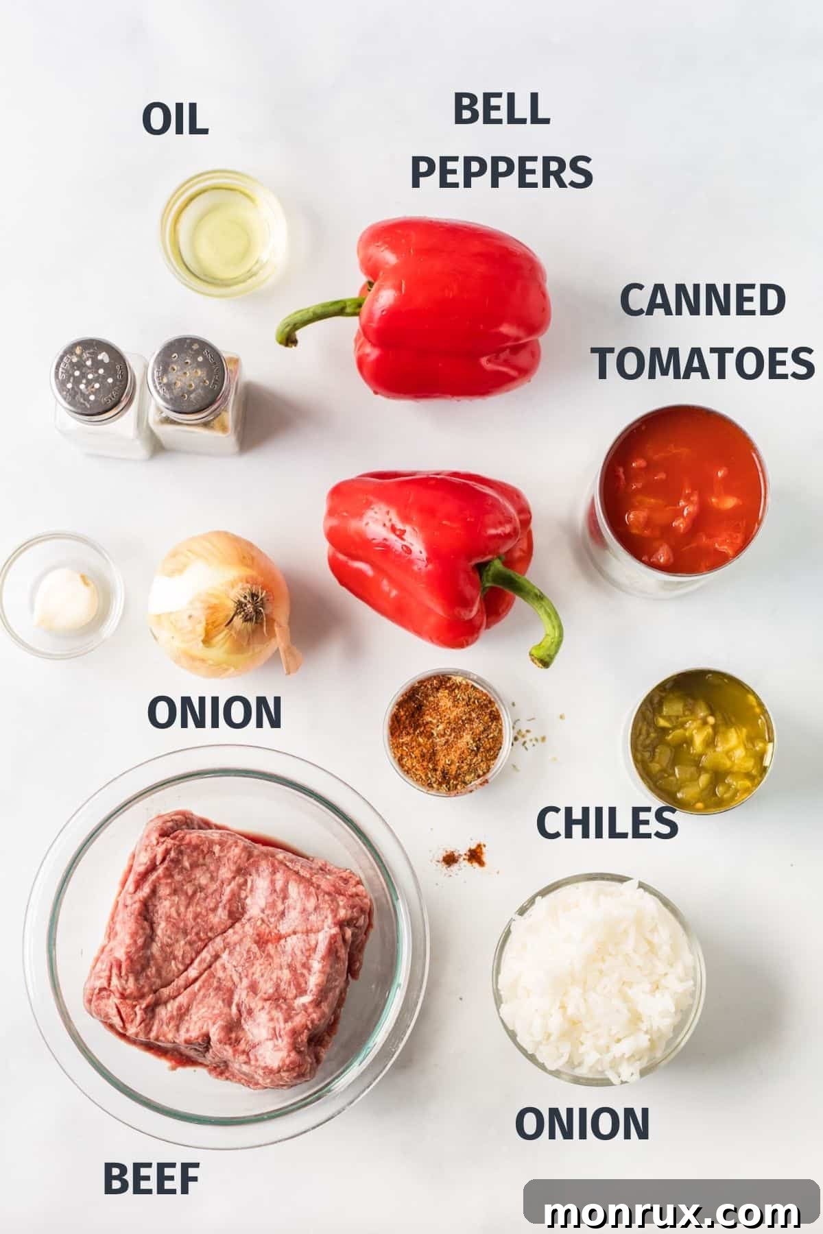A selection of fresh ingredients laid out on a cutting board, including red bell peppers, onion, ground beef, and cans of tomatoes and green chiles, all prepared for the unstuffed pepper skillet recipe.