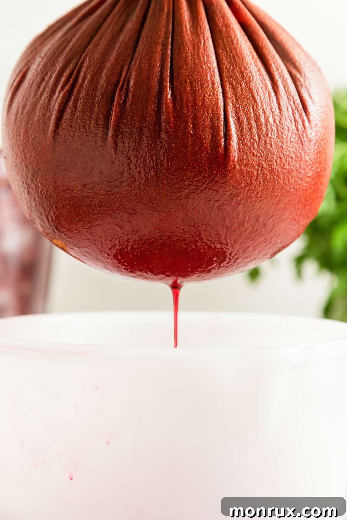 Straining freshly blended beet juice through a nut milk bag.