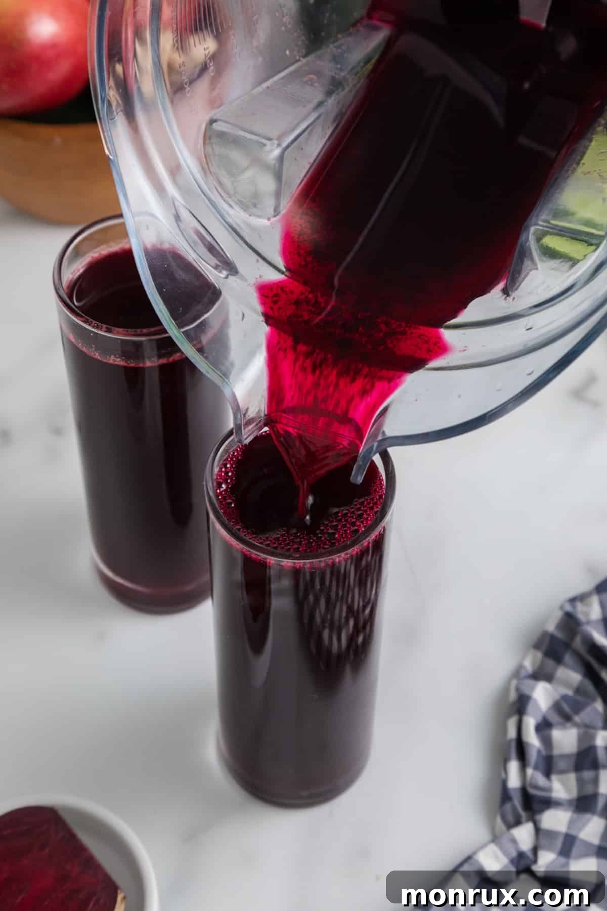 Pouring fresh beet juice into a clear glass.