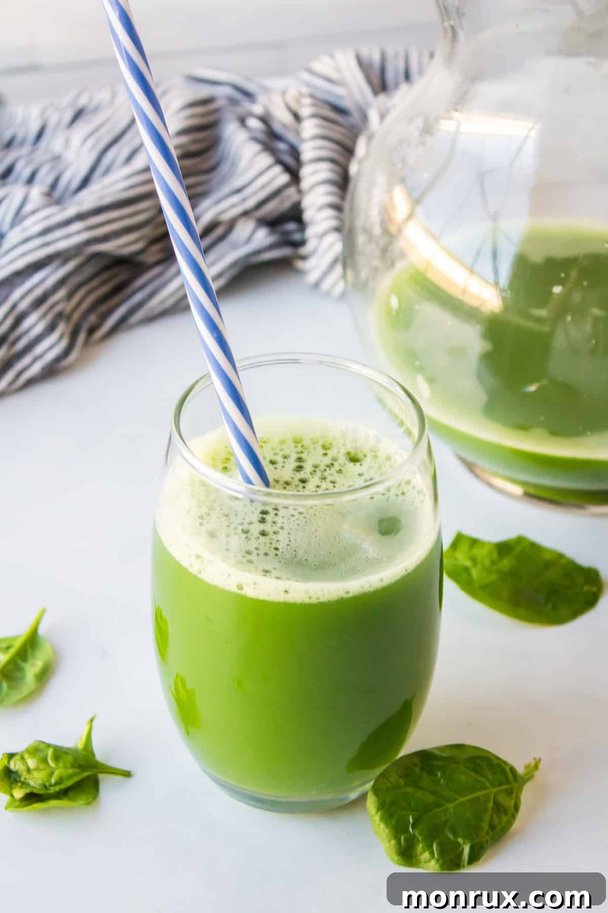 glass of mean green juice with striped straw.