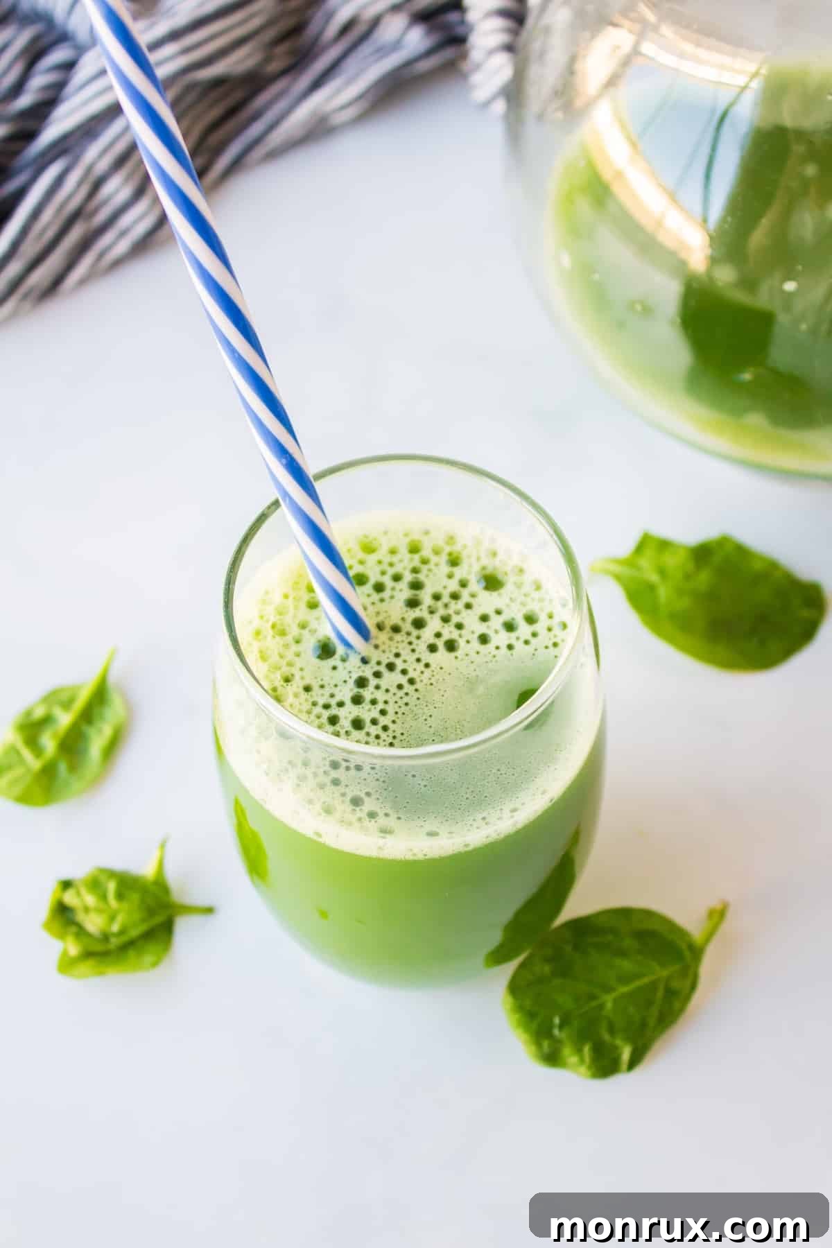 mean green juice in glass with striped straw.